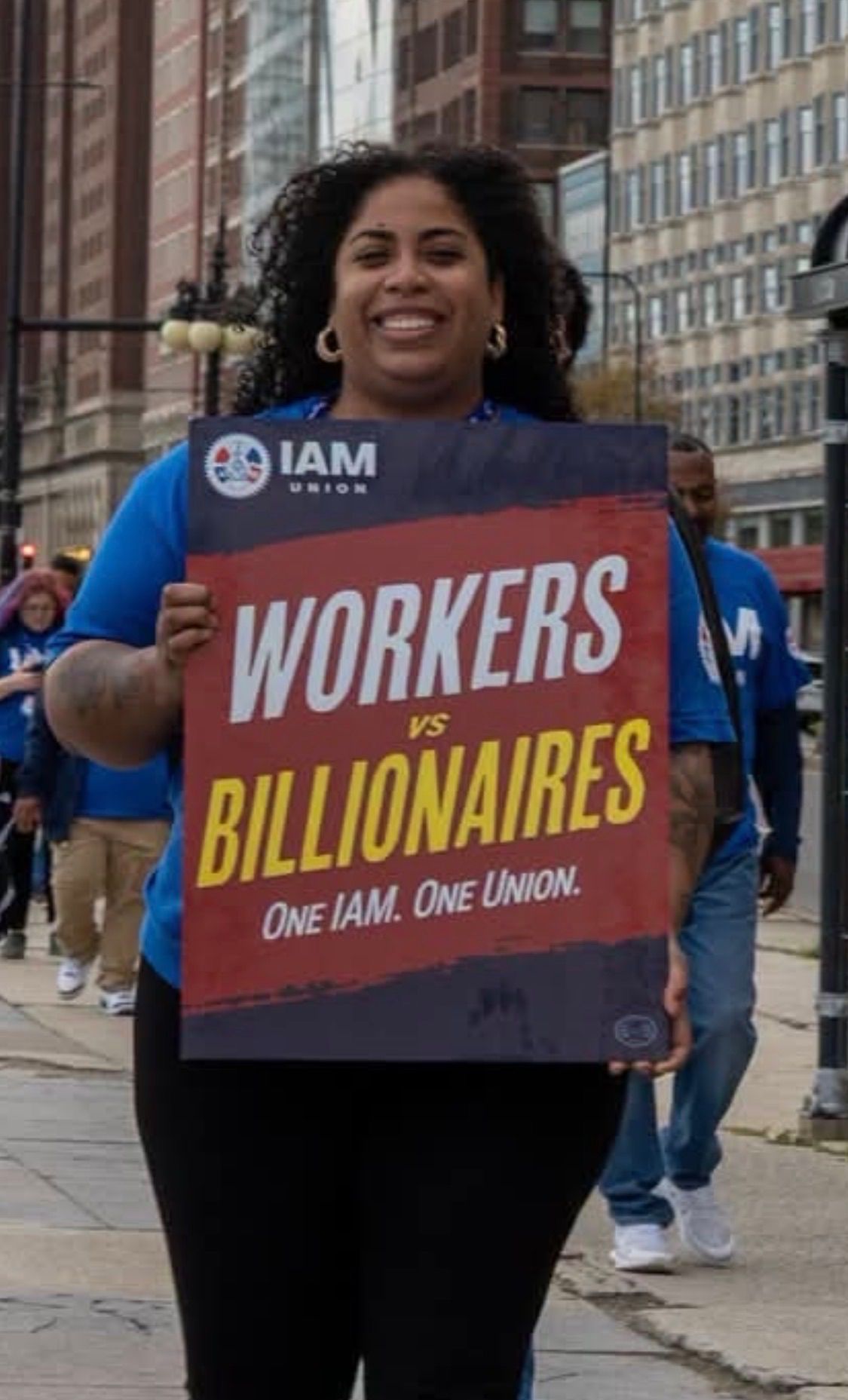Kalani Pone, Trustee candidate, holding an IAM Union Workers vs Billionaires sign